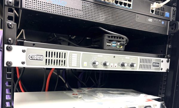 A close-up of a server rack with network equipment, an amplifier labelled Cloud, and a small computer with USB and HDMI ports, surrounded by various cables—captured at the London office of ATIS Foods.