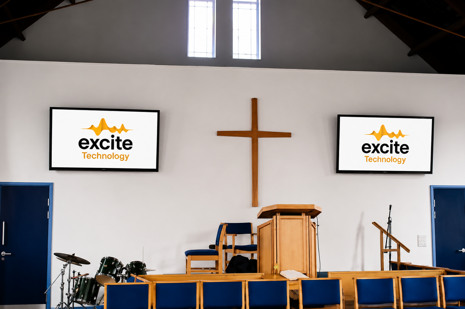 A church sanctuary interior with a wooden cross, pulpit, chairs, musical instruments, and two screens displaying the excite Technology logo in orange and black.